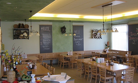Helle Gaststube mit Holztischen und gemütlicher Sitzecke
